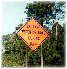 Sign reads: "water on the road during rain"